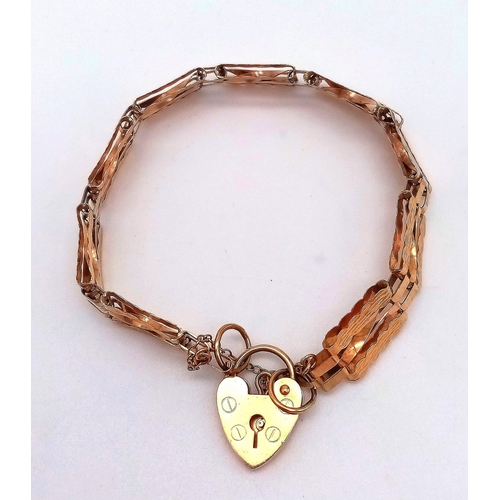 31 - AN ANTIQUE 9K GOLD NICELY PATTERNED GATE BRACELET WITH HEART PADLOCK AND SAFETY CHAIN .   8.1gms