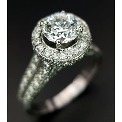 123 - An 18 K white gold ring with a brilliant cut diamond (1.01 carats) surrounded by diamonds on the top... 