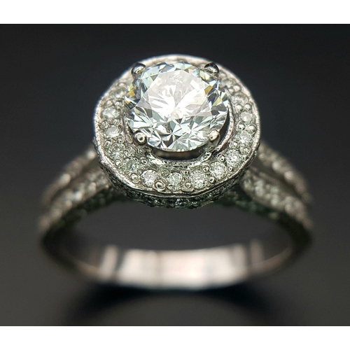 123 - An 18 K white gold ring with a brilliant cut diamond (1.01 carats) surrounded by diamonds on the top... 