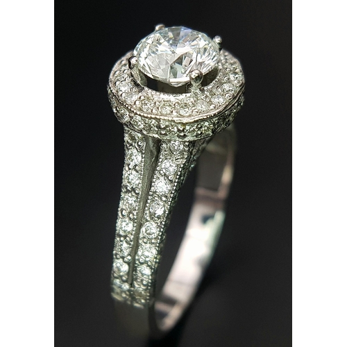 123 - An 18 K white gold ring with a brilliant cut diamond (1.01 carats) surrounded by diamonds on the top... 