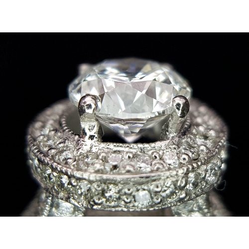 123 - An 18 K white gold ring with a brilliant cut diamond (1.01 carats) surrounded by diamonds on the top... 