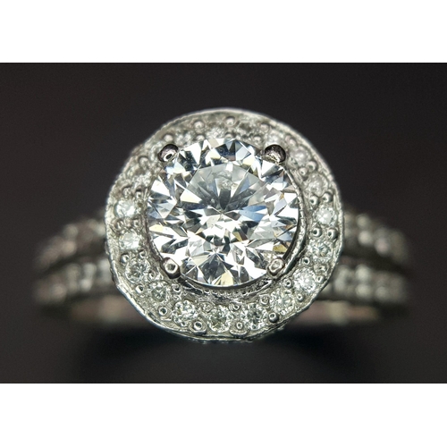 123 - An 18 K white gold ring with a brilliant cut diamond (1.01 carats) surrounded by diamonds on the top... 