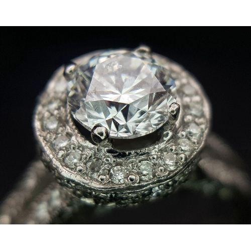 123 - An 18 K white gold ring with a brilliant cut diamond (1.01 carats) surrounded by diamonds on the top... 