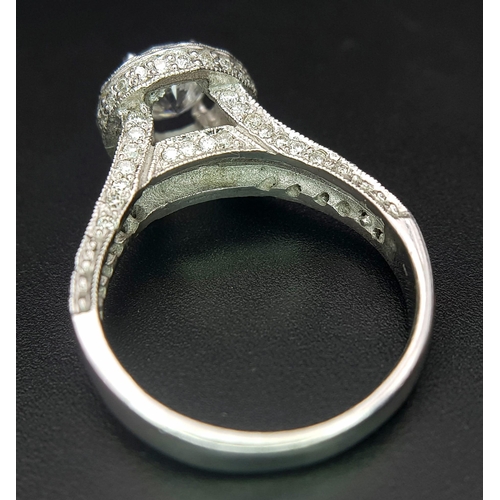 123 - An 18 K white gold ring with a brilliant cut diamond (1.01 carats) surrounded by diamonds on the top... 