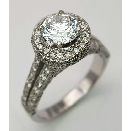 123 - An 18 K white gold ring with a brilliant cut diamond (1.01 carats) surrounded by diamonds on the top... 