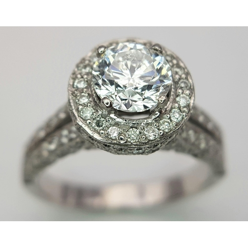 123 - An 18 K white gold ring with a brilliant cut diamond (1.01 carats) surrounded by diamonds on the top... 