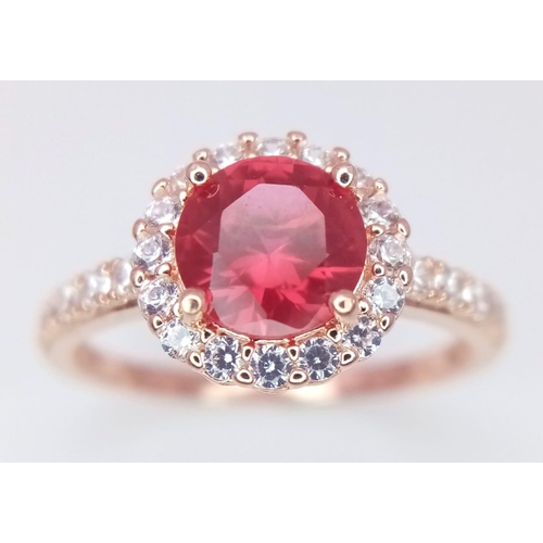 808 - A sterling silver and rose gold plated ring with a simulated ruby surrounded by cubic zirconia. Size... 