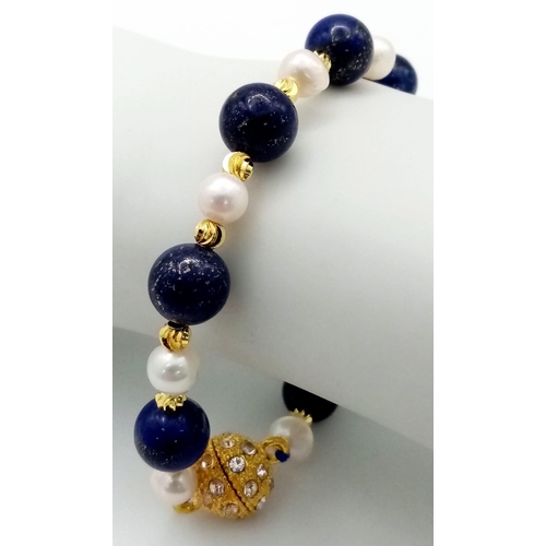 1071 - A Lapis Lazuli and Cultured Pearl Bracelet. Gilded spacers and magnetic glitterball clasp.