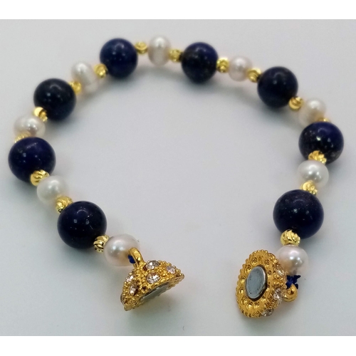 1071 - A Lapis Lazuli and Cultured Pearl Bracelet. Gilded spacers and magnetic glitterball clasp.