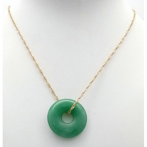 988 - A green jade, donut shaped pendant with a 9 K yellow gold chain, in a presentation box. Total weight... 