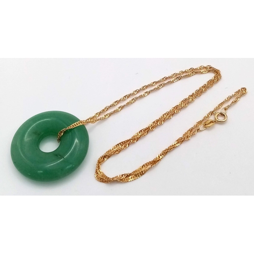 988 - A green jade, donut shaped pendant with a 9 K yellow gold chain, in a presentation box. Total weight... 