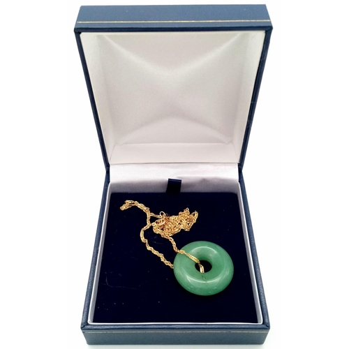 988 - A green jade, donut shaped pendant with a 9 K yellow gold chain, in a presentation box. Total weight... 