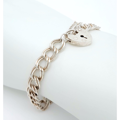 990 - A 925 silver curb link bracelet with safety chain and heart padlock. Total weight 12.7G. Total lengt... 