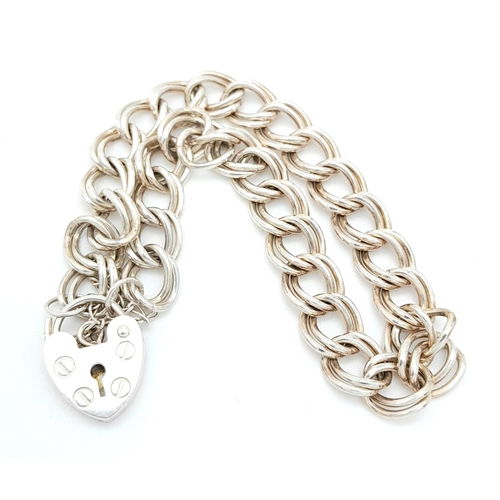 990 - A 925 silver curb link bracelet with safety chain and heart padlock. Total weight 12.7G. Total lengt... 