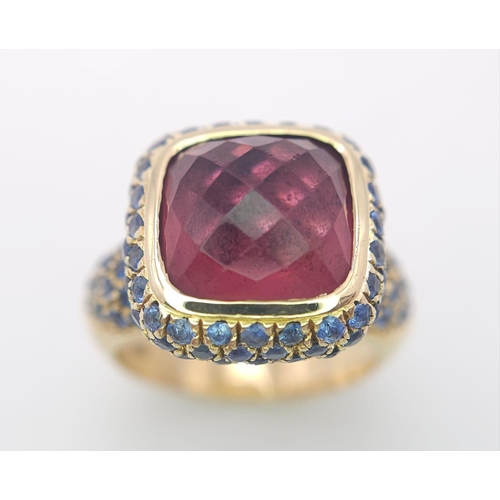 902 - An 18K Yellow Gold Red Tourmaline and Sapphire Ring. A well faceted central tourmaline with a sapphi... 