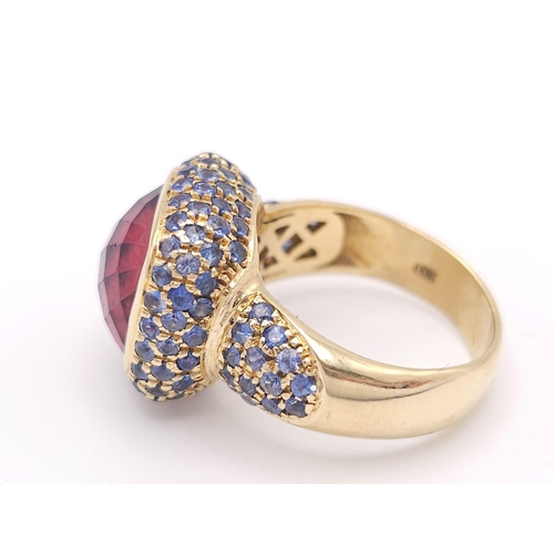 902 - An 18K Yellow Gold Red Tourmaline and Sapphire Ring. A well faceted central tourmaline with a sapphi... 