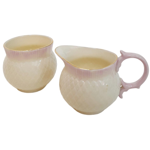 1390 - A rare Irish Belleek sugar bowl and creamer. Cream colour with pink lips and gold ring on top,