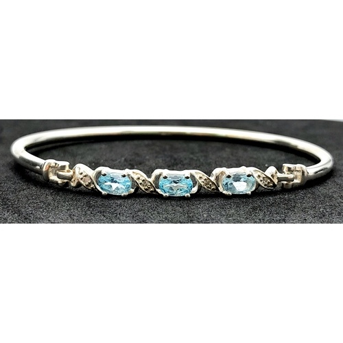 774 - A Sterling Silver Aquamarine Set Bracelet. 6.5cm Inner Width. Set with three 6mm Oval Cut Aquamarine... 