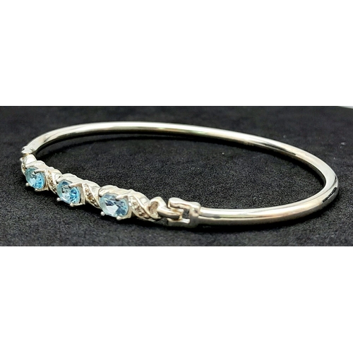 774 - A Sterling Silver Aquamarine Set Bracelet. 6.5cm Inner Width. Set with three 6mm Oval Cut Aquamarine... 