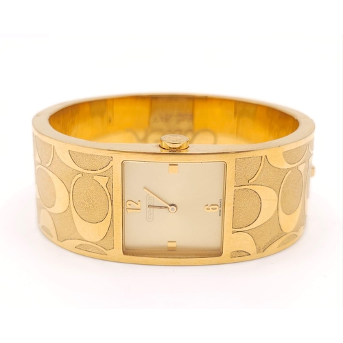 977 - A CLIP BANGLE FASHION WATCH BY COACH , WITH QUARTZ MOVEMENT AND SQUARE GOLD TONE DIAL . COMES WITH O... 