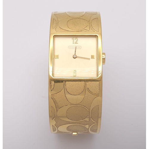 977 - A CLIP BANGLE FASHION WATCH BY COACH , WITH QUARTZ MOVEMENT AND SQUARE GOLD TONE DIAL . COMES WITH O... 