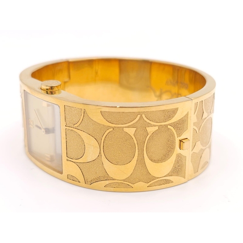 977 - A CLIP BANGLE FASHION WATCH BY COACH , WITH QUARTZ MOVEMENT AND SQUARE GOLD TONE DIAL . COMES WITH O... 