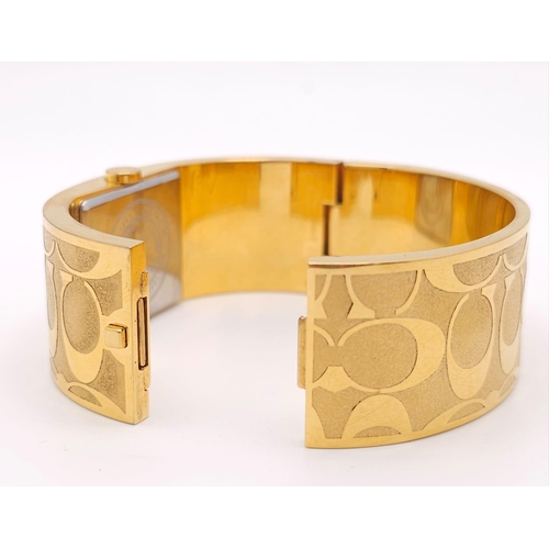 977 - A CLIP BANGLE FASHION WATCH BY COACH , WITH QUARTZ MOVEMENT AND SQUARE GOLD TONE DIAL . COMES WITH O... 