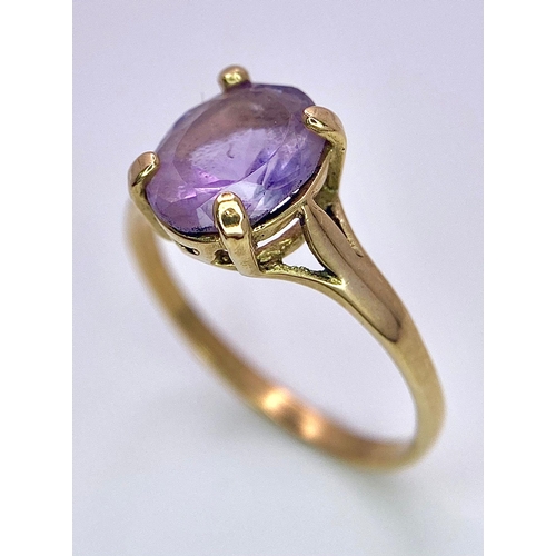 1257 - A 9K GOLD DRESS RING WITH AN OVAL AMETHYST STONE .   1.9gms   size M