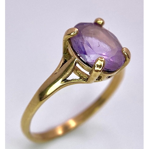 1257 - A 9K GOLD DRESS RING WITH AN OVAL AMETHYST STONE .   1.9gms   size M