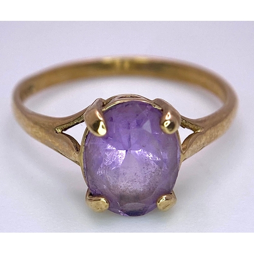 1257 - A 9K GOLD DRESS RING WITH AN OVAL AMETHYST STONE .   1.9gms   size M