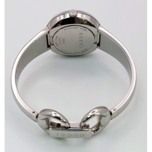 1295 - A Gucci Designer Ladies Quartz Watch. Stainless steel bracelet and case - 27mm. Silver tone dial. In... 