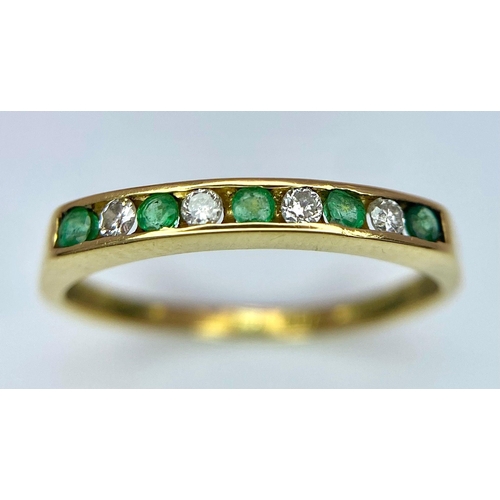 1243 - AN 18K GOLD RING WITH CHANNEL SET EMERALDS AND DIAMONDS .   1.7gms   size L