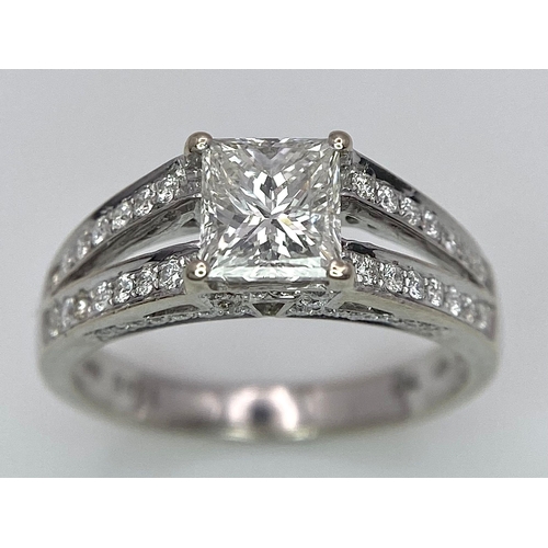 24 - An 18K White Gold Diamond Ring. Central VS2 1ct Princess Cut Near White Diamond with Round Cut Diamo... 