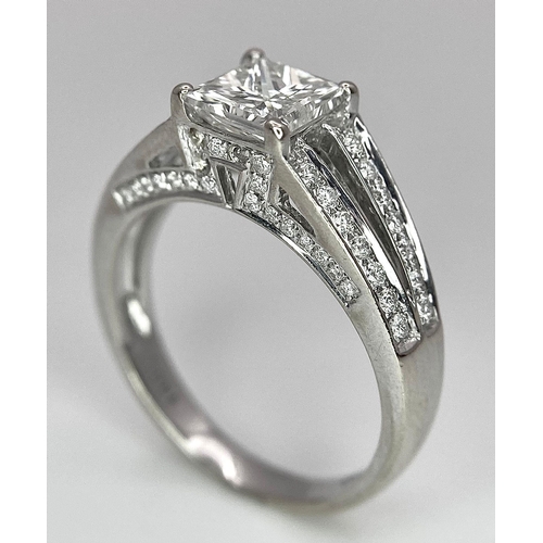 24 - An 18K White Gold Diamond Ring. Central VS2 1ct Princess Cut Near White Diamond with Round Cut Diamo... 