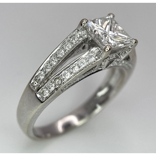 24 - An 18K White Gold Diamond Ring. Central VS2 1ct Princess Cut Near White Diamond with Round Cut Diamo... 