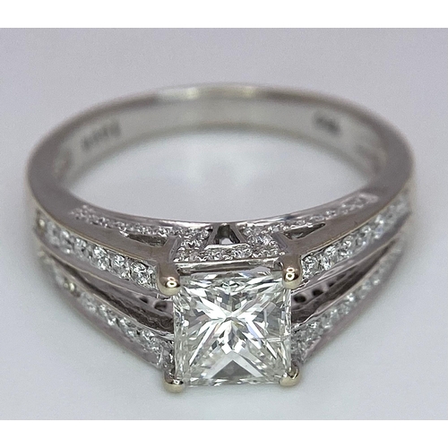 24 - An 18K White Gold Diamond Ring. Central VS2 1ct Princess Cut Near White Diamond with Round Cut Diamo... 
