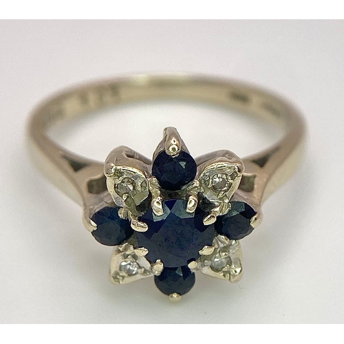 115 - An 18 K white gold ring with a cluster of diamonds and dark blue sapphires.  Size: M, weight: 4 g.
