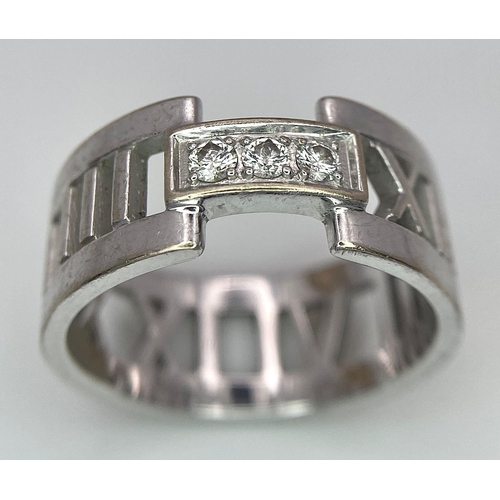 64 - An 18K White Gold Tiffany Atlas Diamond Ring. Pierced Roman numeral decoration. Tiffany mark. Size N... 