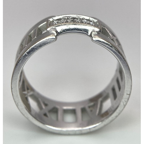 64 - An 18K White Gold Tiffany Atlas Diamond Ring. Pierced Roman numeral decoration. Tiffany mark. Size N... 