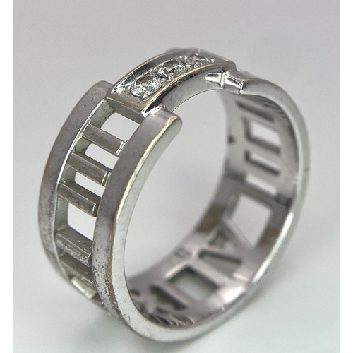 64 - An 18K White Gold Tiffany Atlas Diamond Ring. Pierced Roman numeral decoration. Tiffany mark. Size N... 