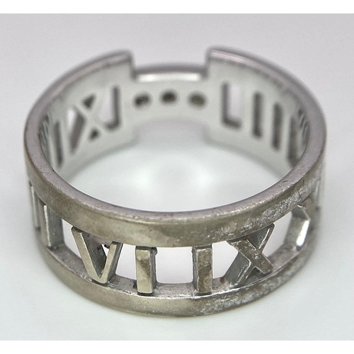 64 - An 18K White Gold Tiffany Atlas Diamond Ring. Pierced Roman numeral decoration. Tiffany mark. Size N... 
