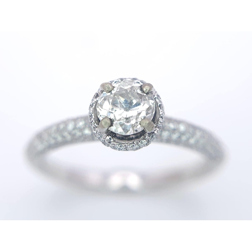 145 - A 14K WHITE GOLD DIAMOND DIAMOND HALO RING WITH FULL SET SHOULDERS AND COLLET. 1.10CT. 2.9G. SIZE M ... 