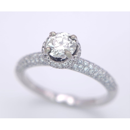 145 - A 14K WHITE GOLD DIAMOND DIAMOND HALO RING WITH FULL SET SHOULDERS AND COLLET. 1.10CT. 2.9G. SIZE M ... 