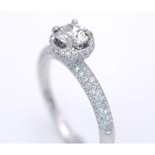 145 - A 14K WHITE GOLD DIAMOND DIAMOND HALO RING WITH FULL SET SHOULDERS AND COLLET. 1.10CT. 2.9G. SIZE M ... 