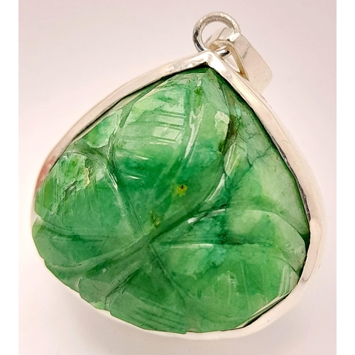 521 - A Carved Trillion Shape 81ct Emerald Pendant set in 925 Silver. 4cm. Comes with a presentation case.... 