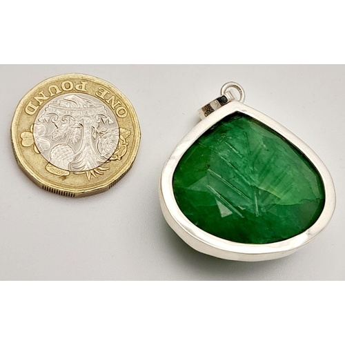 521 - A Carved Trillion Shape 81ct Emerald Pendant set in 925 Silver. 4cm. Comes with a presentation case.... 