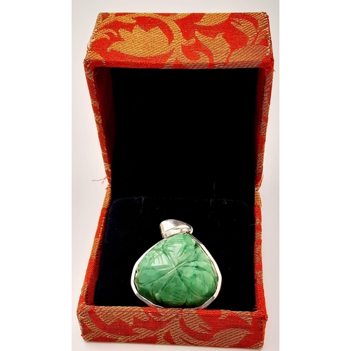 521 - A Carved Trillion Shape 81ct Emerald Pendant set in 925 Silver. 4cm. Comes with a presentation case.... 