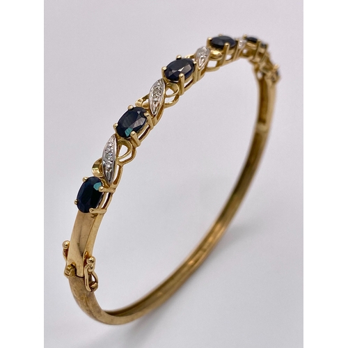 22 - A Vintage 9K Yellow Gold Sapphire and Diamond Bangle. Six oval cut sapphires with diagonal decorativ... 