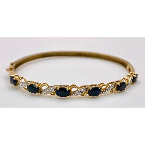 22 - A Vintage 9K Yellow Gold Sapphire and Diamond Bangle. Six oval cut sapphires with diagonal decorativ... 