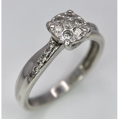 425 - A 9K White Gold Diamond Cluster Ring. Seven small diamonds on a circular base with diamonds on wings... 